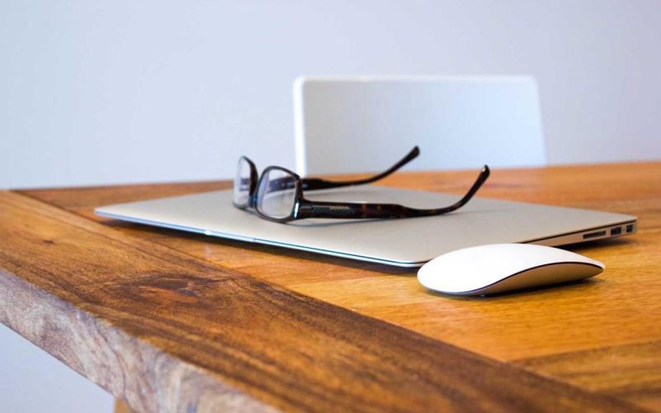 A laptop, glasses and notes on a desk